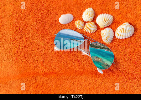 Mode sunglases in der Nähe von Muscheln auf orange Handtuch für den Strand. Konzeptuelle Fotografie vor, die den Sommer Urlaub und Zeit zum Entspannen und Aufladen Teig Stockfoto