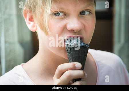 Jugendlich holding Gothic Black Eis in der Hand und schmeckt. Süßes Hässliches Essen. Stockfoto