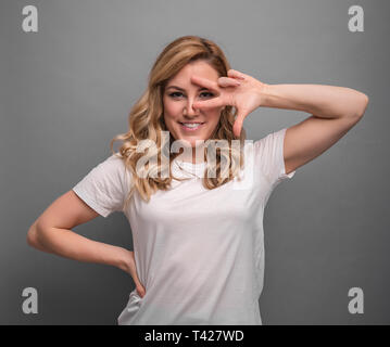 Lustige blondie auf grauem Hintergrund zeigt eine Geste der Tanz. Stockfoto