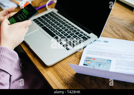 Paris, Frankreich - Apr 9, 2017: Frau Aktivierung auf dem Smartphone Ihren neuen HSBC französische Division mit Arc de Triumph auf der Abdeckung Visa Maestro Card Stockfoto