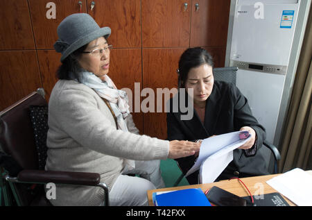 (190413) - TONGLU, April 13, 2019 (Xinhua) - Wu Suhuan (L) bespricht ihre Skript der Film "Kekexili: Mountain Patrol' mit einem Mitarbeiter in Tonglu Zweig von China Blindenbibliothek in Tonglu Grafschaft zu erzählen, der ostchinesischen Provinz Zhejiang, 11. April 2019. Wu Suhuan, 65, ist eine progressive Muskelatrophie Patienten und seit Jahrzehnten gelähmt. Als Erzähler für barrierefreie Filme gewidmet, sie hat bisher schrieb Drehbücher für vier Filme und Sie zusammen mit dem Film für Sehbehinderte seit 2015 beeinträchtigt. "Ich glücklich und in Ihnen helfen erfüllt", sagte Wu. (Xinhua / Weng Xin Stockfoto