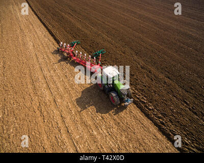 Luftaufnahme der moderne Traktor Arbeiten im landwirtschaftlichen Bereich - Traktor Pflügen und Säen im Agrarbereich Stockfoto