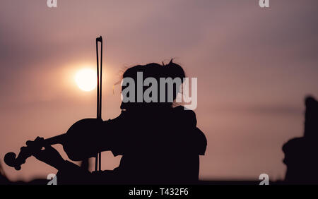 Silhouette der weiblichen Spielen der Violine bei Sonnenuntergang gegen die Sonne - in Prag genommen Stockfoto