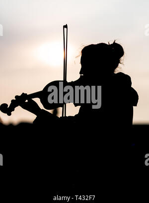 Silhouette der weiblichen Spielen der Violine bei Sonnenuntergang gegen die Sonne - in Prag genommen Stockfoto