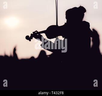 Silhouette der weiblichen Spielen der Violine bei Sonnenuntergang gegen die Sonne - in Prag genommen Stockfoto