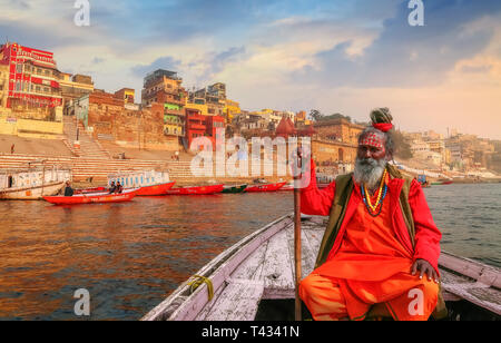 Sadhu baba Sitzen auf einem hölzernen Blick auf alte Varanasi Stadt Architektur mit Ganges ghat bei Sonnenuntergang. Stockfoto