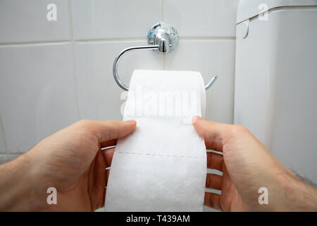 In der Nähe der menschlichen Hand mit Toilettenpapier im Bad Stockfoto