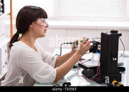 Junge weibliche Techniker tragen Sicherheit Brillen mit Lötkolben Stockfoto