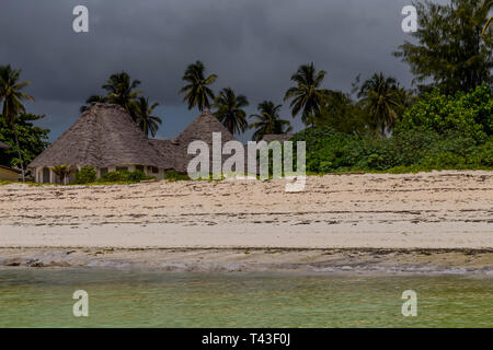 Bungalows und Palmen am weißen Sandstrand an der sunner Tag in Afrika Stockfoto