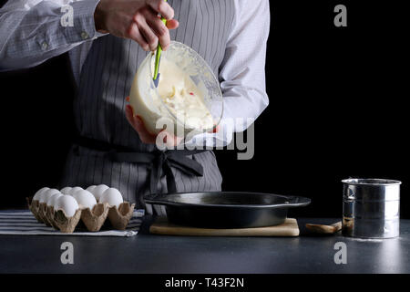 Gießen kuchen Teig in eine Backform. Mann halten Schüssel und Gießen Teig. Stockfoto