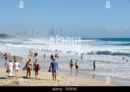 Die Leute am Strand, Schwimmen und Surfen, bei Burleigh Heads, Gold Coast, Queensland, Australien. Surfers Paradise in Distanz. Stockfoto