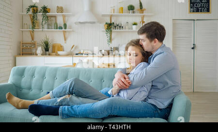 Mann umarmt Dame sitzen auf dem Sofa und Küssen in der Küche. Stockfoto