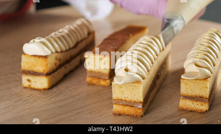 Baker Chef schmückt Keks mit Sahne von gebäckbeutel. Die Hände schließen. selektive Fokus Stockfoto