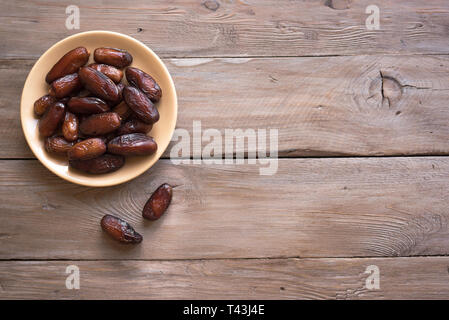 Daten auf der Platte auf Holz- Hintergrund, Ansicht von oben, kopieren. Bio Datteln Früchte. Stockfoto