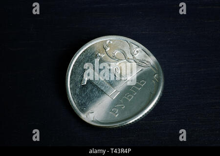Sanktionen und Inflation Konzept. Verbogene Russische Rubel auf dunklem Hintergrund. Stockfoto