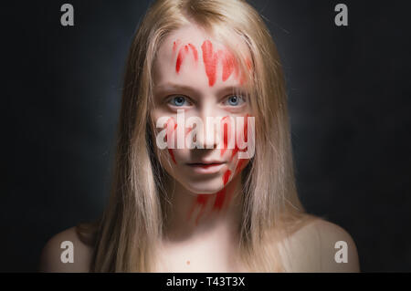 Porträt der jungen Frau mit Farbe im Gesicht auf dunklem Hintergrund. Stockfoto