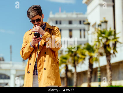 Junge gut aussehender Geschäftsmann in der Stadt auf seinem Gerät Stockfoto