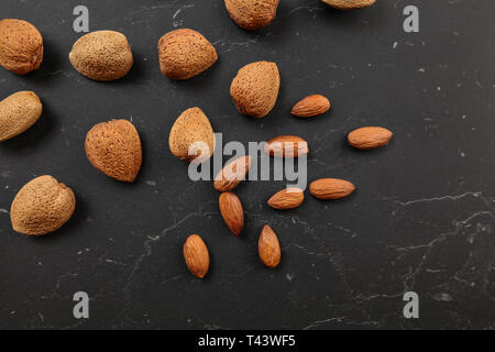 Von oben nach unten anzeigen, Mandeln, ganzen und rissig, auf dunklem Marmor. Stockfoto