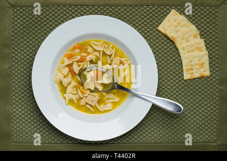 Eine Ansicht von oben aus einer Schüssel Huhn Nudelsuppe und einige Cracker. Stockfoto