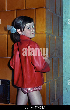 Junge Mädchen tragen rote Jacke warm zu halten, indem sie neben großen traditionellen Keramik Holz Brenner 1960 Ungarn Stockfoto