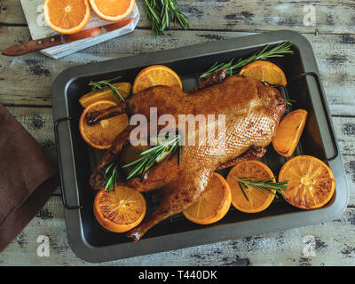 Ganze gebratene Ente mit Orangen, gefüllt mit Äpfeln und Rosmarin auf ein Backblech Stockfoto