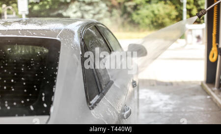 Seite von Silver Auto in Waschstraße gewaschen dienen. Wasser jet stream Sprühen in Luft. Stockfoto