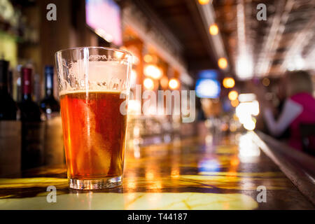 Glas Pint bernsteinfarbenes Bier mit bunten Unschärfe der Bar im Hintergrund Stockfoto