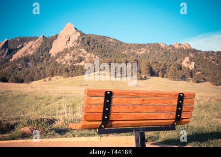 Holz Parkbank mit Blick auf die Flatirons in Boulder, Colorado von Chautauqua Park Stockfoto