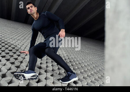 Sport mann Klettern im Beton graue Wand, und dabei seine Ausbildung im städtischen Bereich Landschaft. Konzept der Ziele zu erreichen. Stockfoto