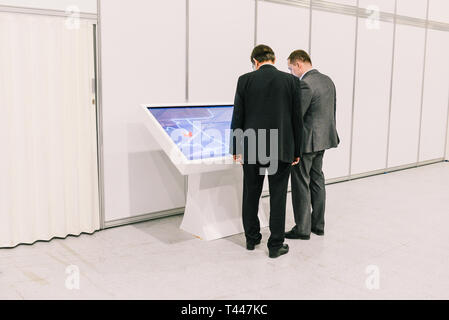 Russland, Stadt Moskau - Dezember 18, 2017: Unternehmer diskutieren über ein Projekt in der Nähe der Touch Monitor. Zwei Männer in Anzügen sprechen in einem Stockfoto