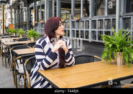 Junge Dame mit langen Haaren allein in der Stadt Street Cafe Stockfoto