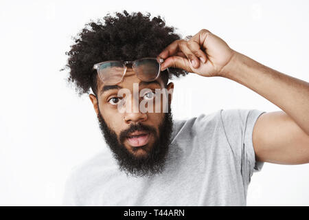 Yo was auf. Portrait von good-looking cool african american bärtigen Kerl mit Afro Frisur, die Brille holding Frames in der Nähe von Stirn als Blick ein Stockfoto