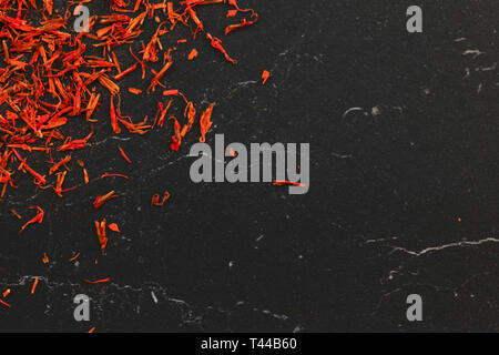 Safran crocus crimson Stigmata und Stile Threads als Gewürz verwendet, auf schwarzem Marmor, flay legen Foto mit Platz für Text rechts Stockfoto