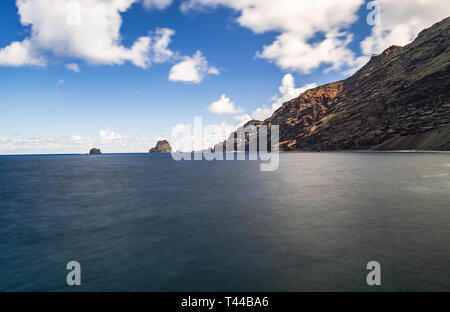 Roques de Salmor, vulkanischen Felsen und Klippen im Atlantischen Ozean, mit blauem Himmel und weißen Wolken, Fotos mit langer Belichtungszeit, Frontera, El Hierro, Kanaren, ist Stockfoto
