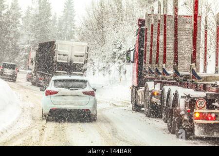 Stau, Autos und Lkws langsam auf Winter Forest Road Mountain Pass während der schweren Schnee Blizzard alle Logos Marken auf Fahrzeuge entfernt Stockfoto