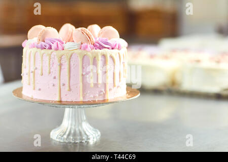 Rosa Kuchen mit Makronen auf dem Tisch eingerichtet. Stockfoto