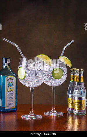 Gin und Tonic, modernen Stil-globe Glas, viel Eis, Scheiben Gurke und Kalk und einem Stroh Stockfoto