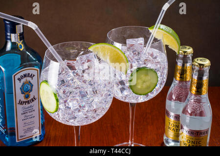 Gin und Tonic, modernen Stil-globe Glas, viel Eis, Scheiben Gurke und Kalk und einem Stroh Stockfoto