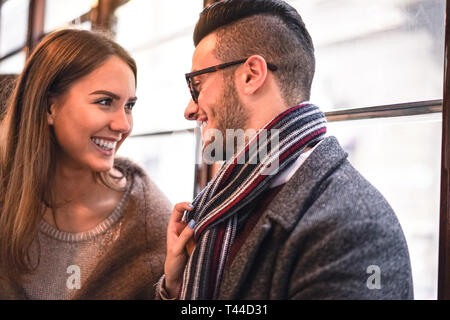 Glückliches Paar lachend, während sie einander im Bus - junge schöne Frau ihrem Freund durch Ziehen Schal neben ihr - Liebe, romantische Konzept Stockfoto