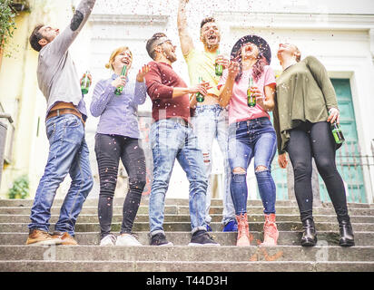 Gruppe der glücklichen Freunde zusammen feiern bis Werfen von Konfetti und trinken Bier - junge Menschen, die eine Partei auf einer Treppe von einem städtischen Bereich Stockfoto