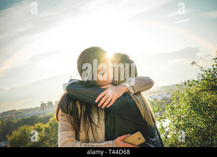 Glückliche Begegnung zweier Freunde umarmen bei Sonnenuntergang im Freien - angenehmen Moment der jungen Schwestern umarmen in der Wüste, während die Sonne auf Sie Stockfoto