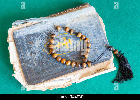 Sorge Perlen über alte orthodoxe Psalm Buch auf grünem Filz Tisch Stockfoto