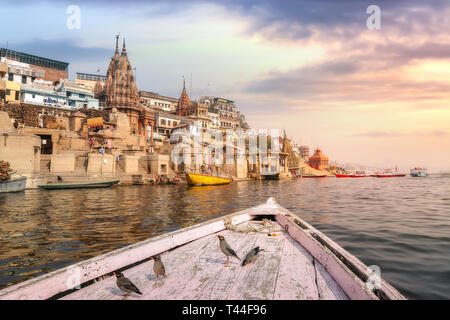Varanasi alten Indien Stadt Architektur auf, die von einem Boot auf dem Fluss Ganges mit Blick auf Zugvögel mit stimmungsvollen Sonnenuntergang Himmel gesehen Stockfoto