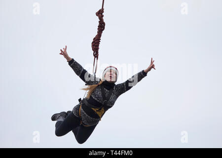 Belarus, Gomel, März 08, 2019. Das Springen von der Brücke zum Seil. Ropejumping. Eine ältere Frau springt aus großer Höhe und Fliegen auf dem Seil in Th Stockfoto