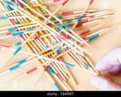 Spieler nimmt einen Stick von Stapel in Mikado Spiel schließen bis auf Holz board Stockfoto