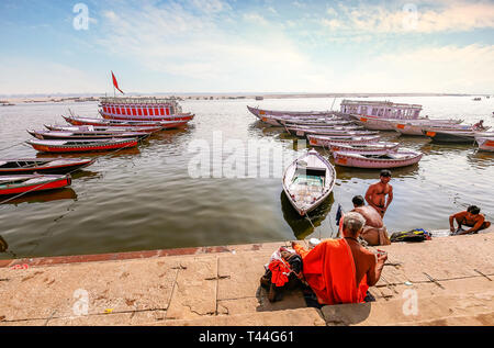 Varanasi Ganges River Bank mit Blick auf die Boote aus Holz und sadhu Baba sitzen auf der Treppe. Stockfoto