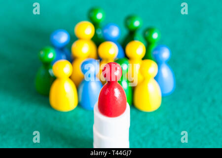 Konzept-Szene - oben sehen Sie eine rote Spielfigur auf Basis über viele verschiedene Schachfiguren auf grünem Filz Tisch. Konzentrieren Sie sich auf die roten Spielball Stockfoto