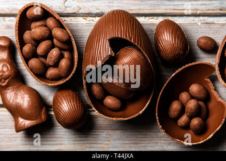 Schokolade Osterhasen Hasen und Eier auf einem rustikalen Holzmöbeln Hintergrund Stockfoto