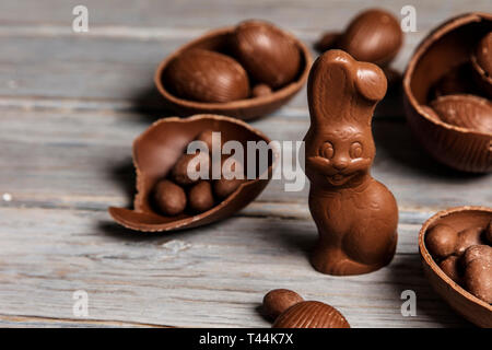 Schokolade Osterhasen Hasen und Eier auf einem rustikalen Holzmöbeln Hintergrund Stockfoto