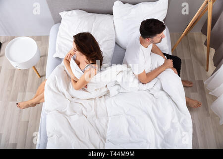 Hohes Ansehen der Verzweifelten Ehepaar Rücken an Rücken auf dem Bett Stockfoto